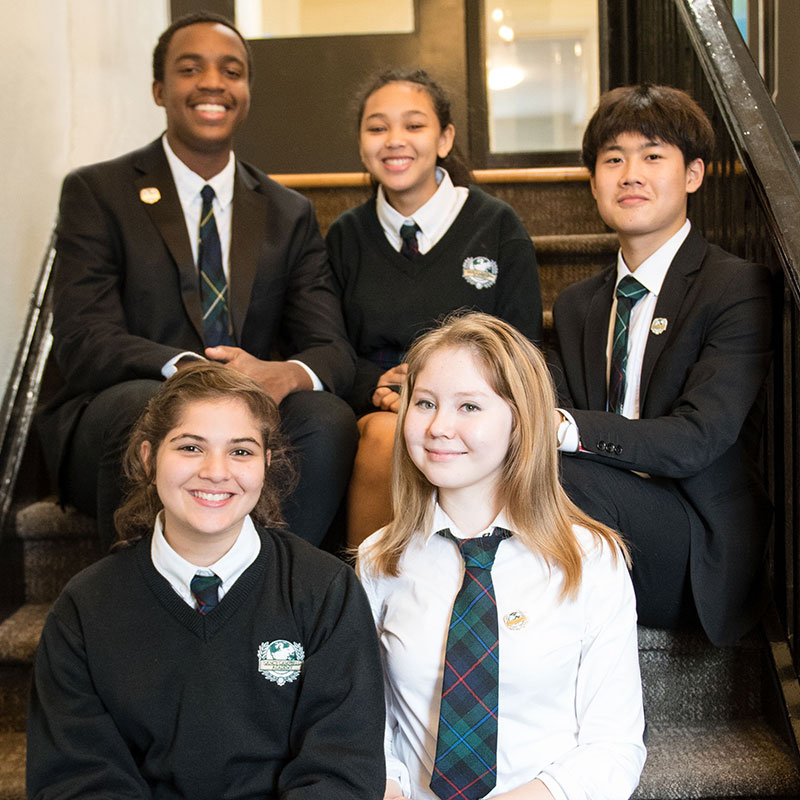 5 students in uniform sitting in NCA stairwell